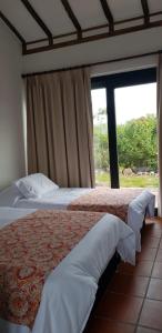 a bedroom with two beds and a large window at El Garabandal in Villa de Leyva
