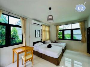een slaapkamer met 2 bedden, een bureau en ramen bij home near MRT Tha Phra Villa sookkasem in Bangkok Yai