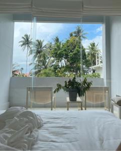 a bedroom with a bed and a window with palm trees at Saffron Robes Living in Hikkaduwa