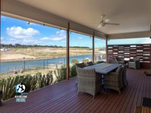 a deck with a table and chairs and a view of the water at Luxury Waterfront Holiday Home - Bring the Boat! in Hindmarsh Island