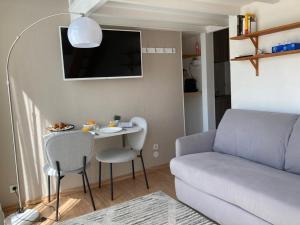 uma sala de estar com um sofá e uma mesa com cadeiras em Chambre indépendante en face de la Gare Lille Flandres em Lille