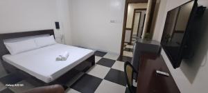 sypialnia z łóżkiem, telewizorem i podłogą wyłożoną szachownicą w obiekcie Bayside Exceel Hotel w mieście Puerto Galera