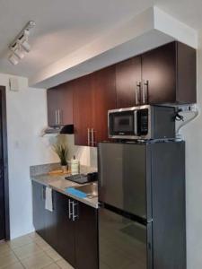 a kitchen with a microwave on top of a refrigerator at Casa REYNA at KASARA Urban Residences in Manila