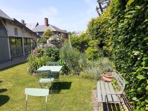 a garden with a table and chairs in the grass at Au p'tit jardin in Saint-Sylvestre-de-Cormeilles