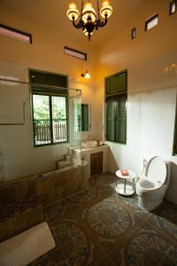 La salle de bains est pourvue de toilettes, d'une baignoire et d'un lavabo. dans l'établissement วิลล่าขุนวิเชียรพานิช, à Phetchaburi