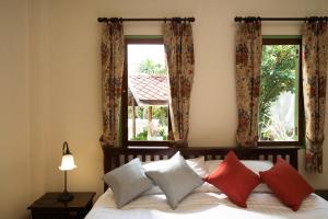 een slaapkamer met een bed met rode en witte kussens bij วิลล่าขุนวิเชียรพานิช in Phetchaburi