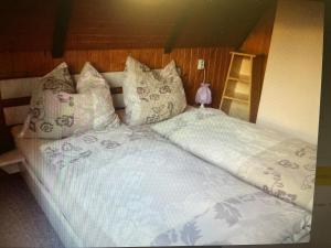 ein großes Bett mit weißer Bettwäsche und Kissen in der Unterkunft Ferienhaus Günther Harzgerode/Schielo in Schielo