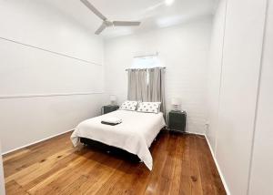 a white bedroom with a bed and wooden floors at Townsville Suites in Townsville