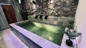 a bathtub in a bathroom with a green at Fouralivin in Kesiman