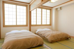 two beds in a room with two windows at ヴァンテアン舎（vingt et un house） in Biei