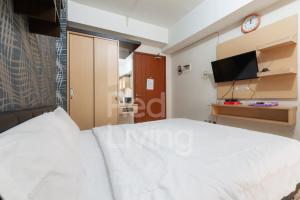 a bedroom with a white bed and a tv at RedLiving Apartemen Green Lake View Ciputat - Aurora Rooms in Pondokcabe Hilir