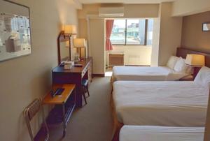 東京にあるシティペンション ゼムのベッド2台とデスクが備わるホテルルームです。