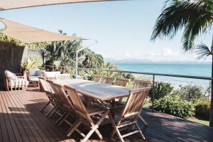 una terraza de madera con mesa, sillas y el océano en Wategos Villa en Byron Bay