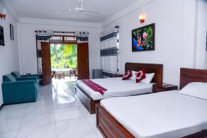 a hotel room with two beds and a chair at Villa A.SMS in Induruwa
