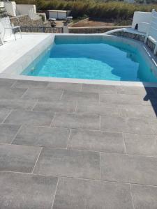 uma piscina com piso de pedra e uma piscina em Adonis Rooms em Kalo Livadi