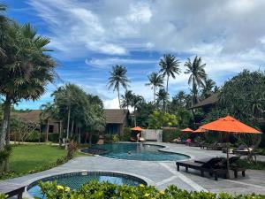 a pool with benches and umbrellas in a yard at Aonang Hill Krabi-SHA Extra Plus in Ao Nang Beach