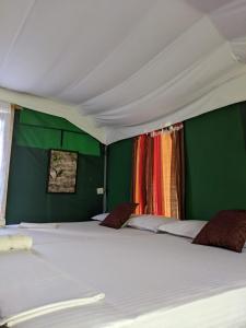 ウィルパットゥにあるNirvaan Safari Lodgeの緑の壁の客室で、白い大型ベッド1台が備わります。