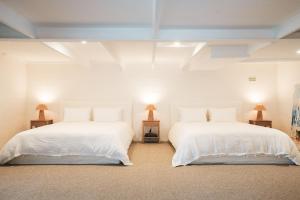 two beds in a room with white walls and two lamps at Wategos Villa in Byron Bay