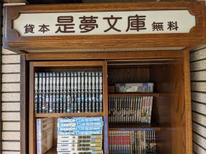 een bord boven een boekenplank met boeken bij City Pension Zem in Tokyo