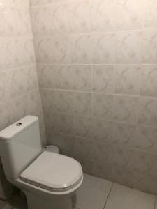 a bathroom with a toilet and a white tiled wall at Hotel Nikea Paradiso in Kutaisi