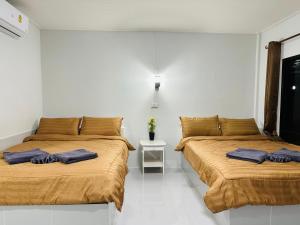 dos camas sentadas una al lado de la otra en una habitación en บ้านโกจุยรีสอร์ต, 