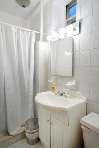 a white bathroom with a sink and a mirror at Lovely Studio in Heart of NYC (Midtown West) in New York