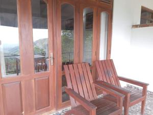 2 chaises en bois assises devant une porte dans l'établissement Divine View Homestay, à Ella