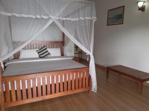 a bedroom with a canopy bed and a bench at Divine View Homestay in Ella