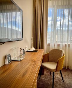 Habitación con escritorio de madera, silla y ventana. en Hotel Mepas en Mostar