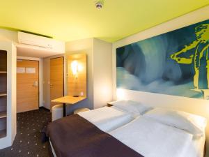 a hotel room with a bed and a painting on the wall at B&B Hotel Krefeld in Krefeld