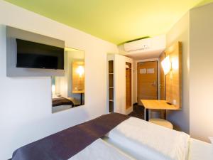 a hotel room with a bed and a desk and a tv at B&B Hotel Krefeld in Krefeld