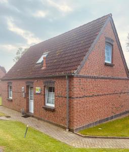 een rood bakstenen huis met een bruin dak bij Ferienhaus Tina in Wirdum