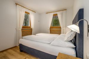 a bedroom with two beds and two windows at Ferienwohnung Mair am Bach in Brunico