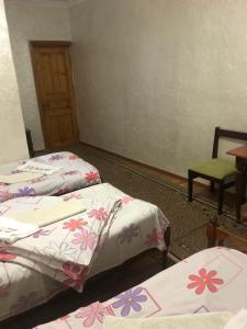 a room with three beds and a table and a chair at Hotel Nikea Paradiso in Kutaisi