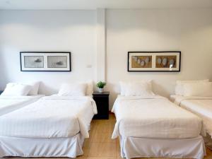 ムーシにあるThe White Chalet Khaoyaiの白い壁のドミトリールーム ベッド3台