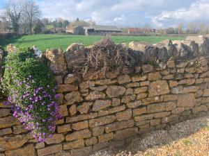 a stone retaining wall with purple flowers on it at The Milking Sheds in Tytherington