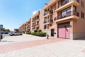 een gebouw met een roze garage en een parkeerplaats bij Mar y Sol Salinetas in Telde