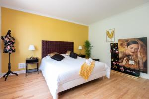 a bedroom with a white bed and a painting on the wall at Gîte Villa La Chèvrerie centre in Épinal