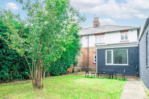 a house with a tree and two chairs in the yard at Charming 2-Bedrooms Apartment with a Garden at Abingdon in Oxford