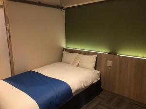 a small bed in a room with a green wall at Hotel Lantana Naha Matsuyama in Naha