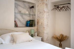 a bedroom with a white bed and a stone wall at Suite Cavour 30 in Ostuni