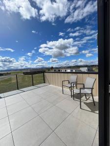 a balcony with two chairs and a view of a field at The Little Lake House in Te Anau