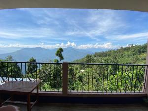 a balcony with a table and a view of mountains at Golden Apple Garden Homestay by StayApart in Kalimpong