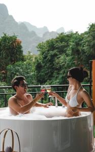 a man and woman sitting in a bath tub with glasses of wine at Phu Siab Mhok@KhaoSok in Khao Sok