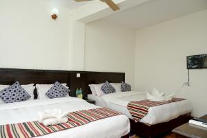 um quarto com 2 camas com almofadas azuis e brancas em Hotel Admire Pokhara Pvt. Ltd. em Pokhara