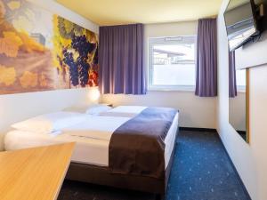a hotel room with two beds and a tv at B&B Hotel Heilbronn in Heilbronn
