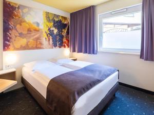 Schlafzimmer mit einem Bett mit Wandgemälde in der Unterkunft B&B Hotel Heilbronn in Heilbronn
