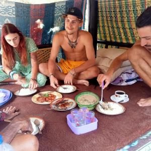 SUNRISE BUKIT ASAM HOMESTAY في كوتا لومبوك: مجموعة من الناس جالسين على الأرض يأكلون الطعام