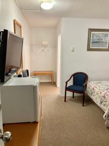 1 dormitorio con 1 cama, TV y silla en Motel 99, en Grand Forks