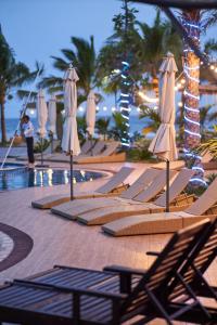 a group of lounge chairs and umbrellas next to a pool at Hodota Cam Bình Resort & Spa - Lagi Beach in Vĩnh Thạnh